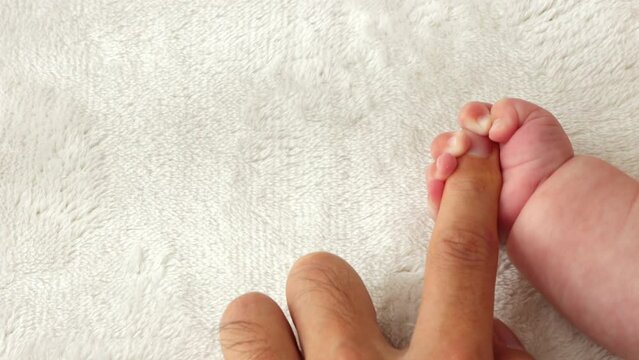 父親の指を握りしめる赤ちゃんの右手（0歳2か月、男の子、日本人）