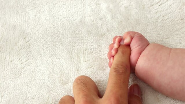 父親の指を握りしめる赤ちゃんの右手（0歳2か月、男の子、日本人）