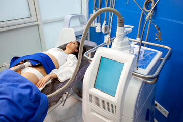 coolsculpting procedure in cosmetology clinic, girl patient lies on couch connected to the machine to remove fat