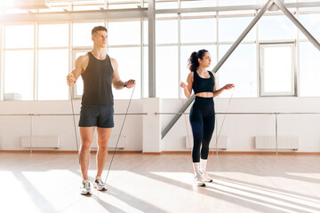 athletic couple in training jump rope in the gym in the morning, man coach and woman go in for...