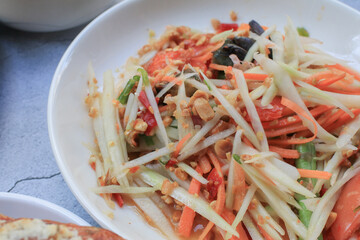 Thai papaya salad, Som Tum, Spicy green papaya salad with vegetables on table. Famous Thai food. Asian food style