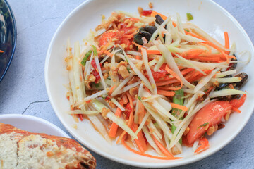 Thai papaya salad, Som Tum, Spicy green papaya salad with vegetables on table. Famous Thai food. Asian food style