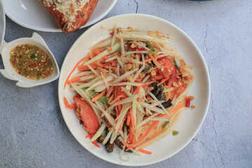 Thai papaya salad, Som Tum, Spicy green papaya salad with vegetables on table. Famous Thai food. Asian food style