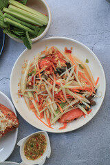 Thai papaya salad, Som Tum, Spicy green papaya salad with vegetables on table. Famous Thai food. Asian food style