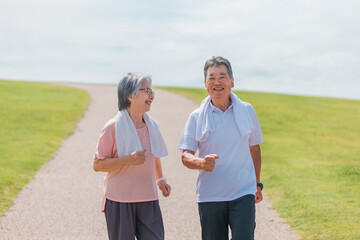 公園でウォーキング・有酸素運動する高齢者夫婦（シニア・男女）
