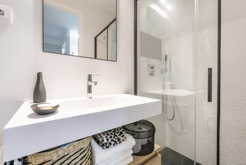 Bathroom with one-piece white resin sink, black edged wall mirror and shower tray with glass screens