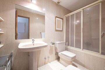 Fototapeta na wymiar Bathroom with matching pedestal porcelain sink, walk-in shower with tub, large frameless mirror, and light tile