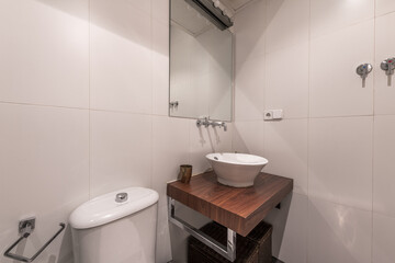 Small bathroom with porcelain sink on dark wood paneling and mirrors with thin black edges and overhead light bulbs