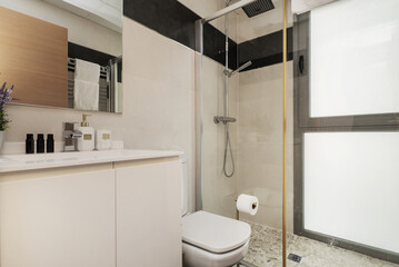 Small bathroom with a white porcelain sink on a white cabinet with doors and a sliding shower cubicle