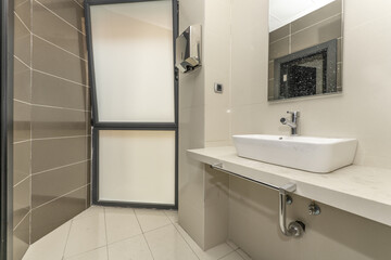 Small bathroom with a white porcelain sink on a long light stone countertop and a large window with translucent glass