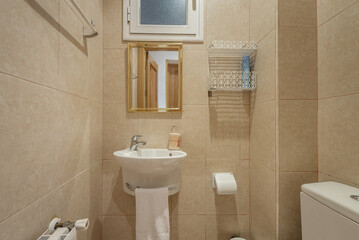 Small bathroom with a white porcelain sink attached to the wall and a small mirror with a gold frame