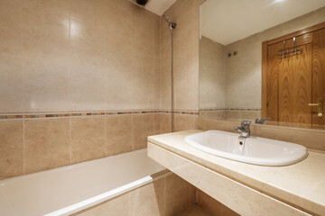Bathroom with cream marble sink without cabinet with mirror integrated into the wall and with a long bathtub
