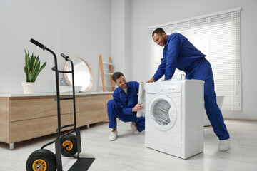 Obraz na płótnie Canvas Male movers with stretch film wrapping washing machine in bathroom. New house