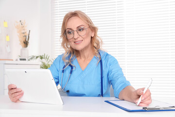 Doctor with glasses and tablet consulting patient in clinic. Online medicine concept