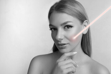 Laser mole removal. Woman with ray pointed at her skin during procedure on grey background, space...