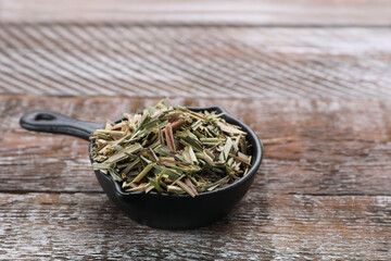 Fototapeta na wymiar Small saucepan with aromatic dried lemongrass on wooden table. Space for text