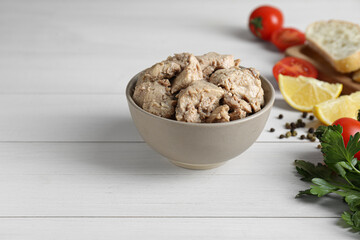 Bowl of tasty cod liver and different products on white wooden table. Space for text