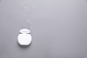 Container with dental floss on grey background, top view. Space for text