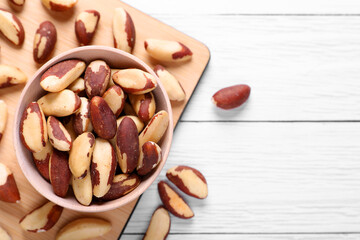Delicious Brazil nuts on white wooden table, flat lay. Space for text