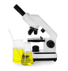 Laboratory glassware with yellow liquid and microscope isolated on white