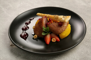 Plate with delicious chicken, parsnip and strawberries on grey table. Food stylist