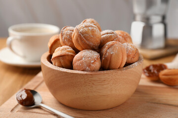 Bowl of delicious nut shaped cookies with boiled condensed milk on wooden table, closeup