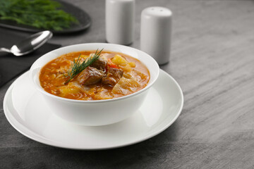Tasty cabbage soup with meat, carrot and dill on black table, closeup. Space for text