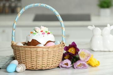 Fototapeta na wymiar Easter basket with painted eggs and tasty cake near flowers on white marble table indoors