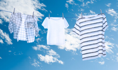 Different clothes drying on washing line against sky