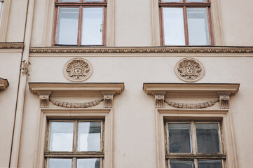 Four old windows with wooden frames and mascarons on the wall. Neoclassical building, facade of an old house in Lviv, Ukraine.