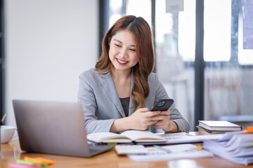 Smiling young Asian business woman executive looking at smartphone using cellphone mobile cell...