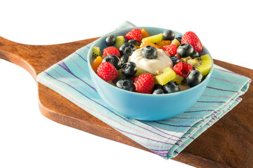 On a kitchen wooden board in a blue bowl, a delicious fresh healthy fruit salad for breakfast.Isolated on a white background.
