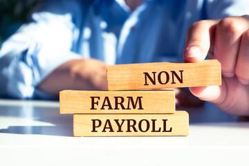 Close up on businessman holding a wooden block with "NON FARM PAYROLL" message