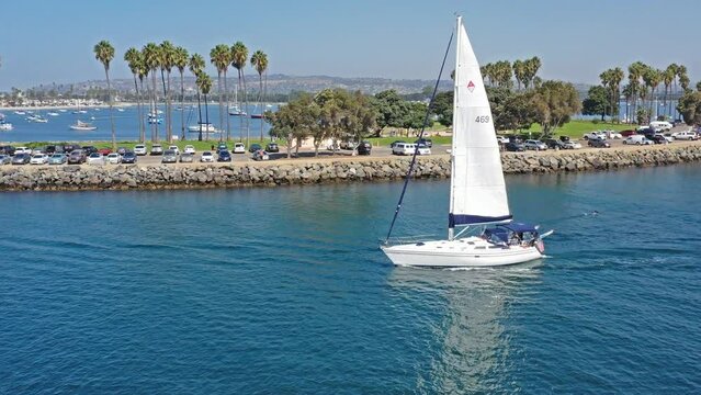 Panning Drone shot of Sail Boat heading out of San Diego bay over to Sail boats ancored in the harbor in California.