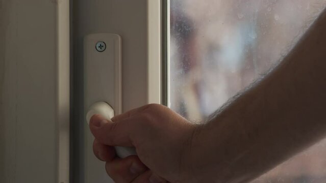 close up view of man close balcony door by handle. Sunny day, balcony door closes.