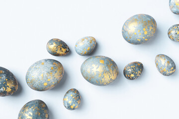 Blue Easter eggs with golden spots on light blue Easter background. Chic Easter greeting card, flat lay, Diagonal composition.