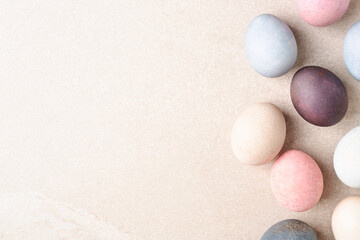 Natural dyed Easter eggs border on beige table. Eco concept, copy space. Pastel pale colors.