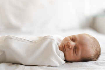 Half body shot of caucasian hairy brunet cute newborn baby yawning.One or two week child on bed indoor.Copy space.