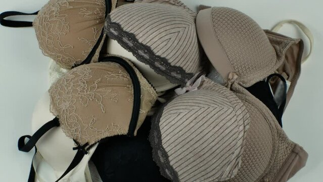 A pile of different classic women's bras on a light background close-up. Underwear beauty, comfort, fashion. Creative beauty concept of women's underwear