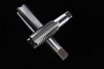 closeup of tap four flute tool for cutting metal threads right screws. Material high speed steel. Isolate on black background.