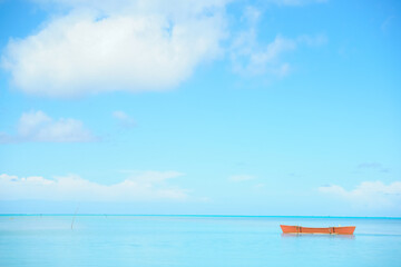 Orange color outrigger canoe on turquoise tropical water