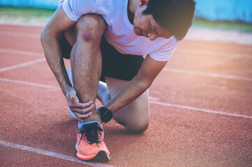 Man runner has twisted ankle injury while practice marathon run at the racetrack.
