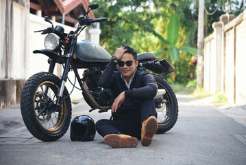Naklejka na ściany i meble Asian man motorbike in black leather jacket travel rider trip. Handsome Men wear sunglass outdoor lifestyle freedom rider. Men trendy hipster cool person. Young asian man hobby ride with motor bike