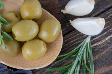 olives with spices and rosemary in a wooden spoon