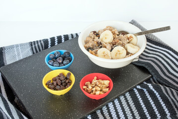 Bowl of Oatmeal with Blueberries, Raisins and Walnuts on Black Granite