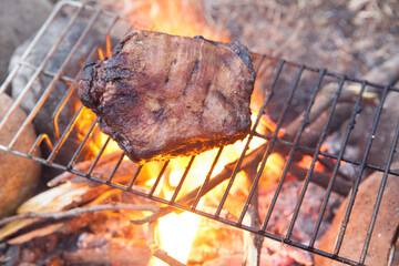 焚き火でイノシシの肉を焼く