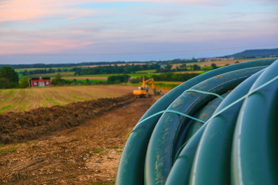 Plumbing installation. Pipe laying. Water pipes and yellow excavator in the field. Carrying out water construction work.Bringing water to the house.