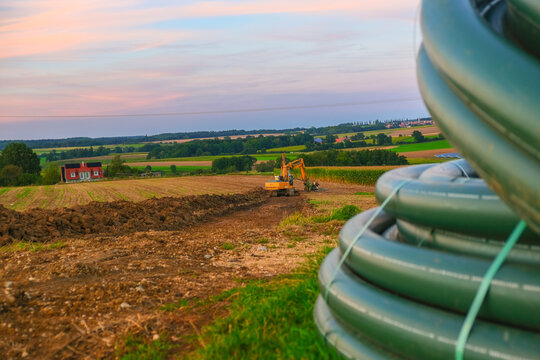 Pipe laying. Water pipes and yellow excavator in the field. Carrying out water construction work.Plumbing installation.Bringing water to the house.