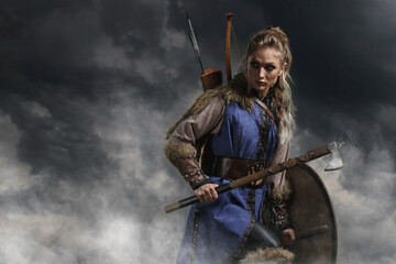 Beautiful female viking woman warrior in battle with ax and bow with arrows. Amazon fantasy blonde - 573419514