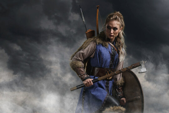 Beautiful female viking woman warrior in battle with ax and bow with arrows. Amazon fantasy blonde